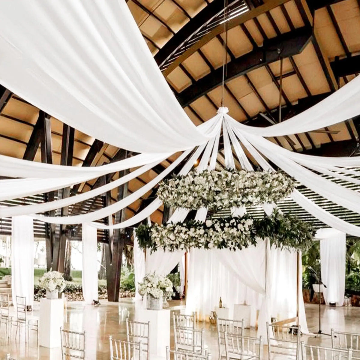 A wedding or event venue decorated with white sheer chiffon draping fabric suspended from the ceiling.