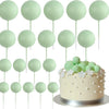 A collection of twenty light green ball cake toppers on sticks arranged in rows.