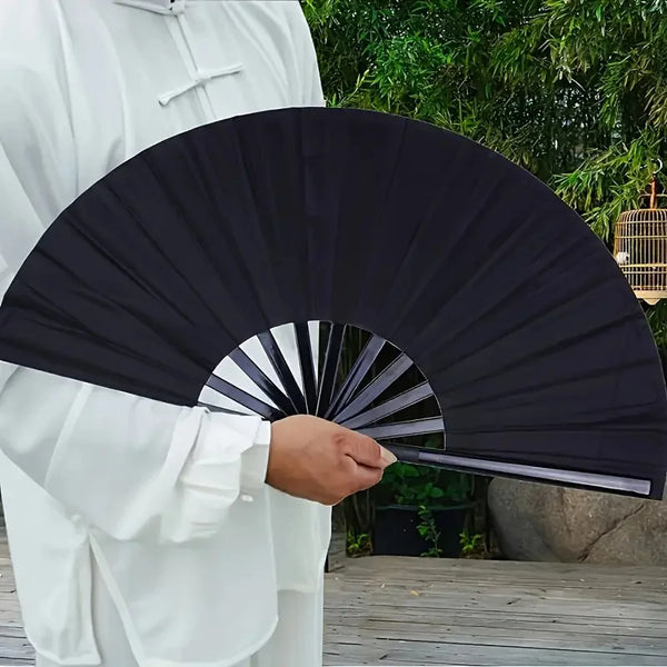 Una persona sostiene un abanico plegable negro, similar a un abanico de kung fu, en una túnica blanca.