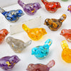 A collection of colorful natural crystal bird statues in various shades including purple, blue, orange, and yellow.