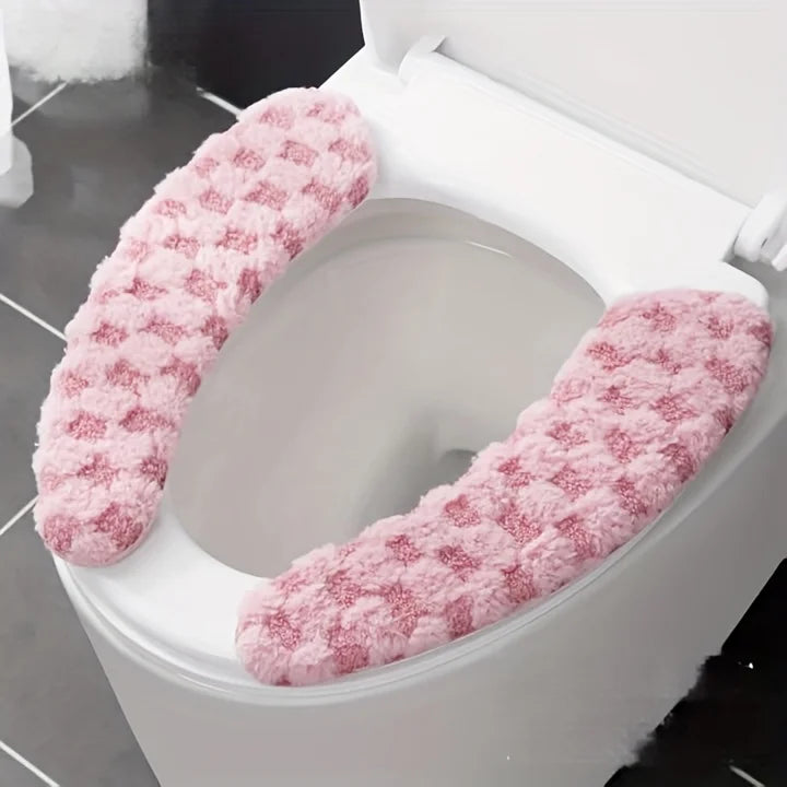 A white toilet seat with a pink, fluffy washable cushion cover installed.