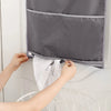 A person is hanging a gray foldable laundry basket organizer on a white door, demonstrating its use.