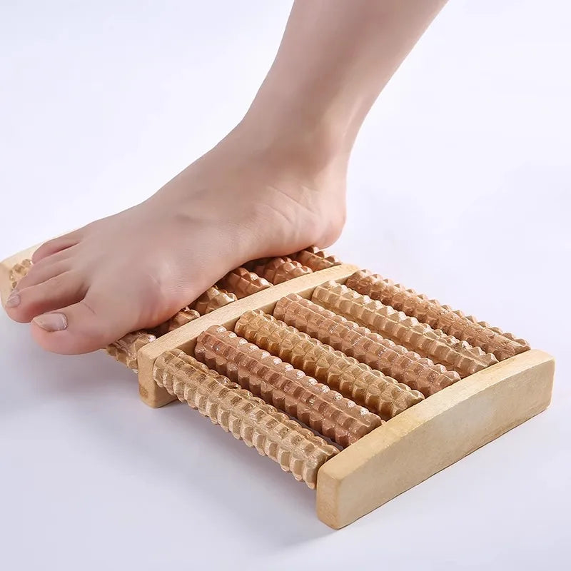 Holz-Fußmassagerolle mit parallelen Rollen neben einem nackten Fuß