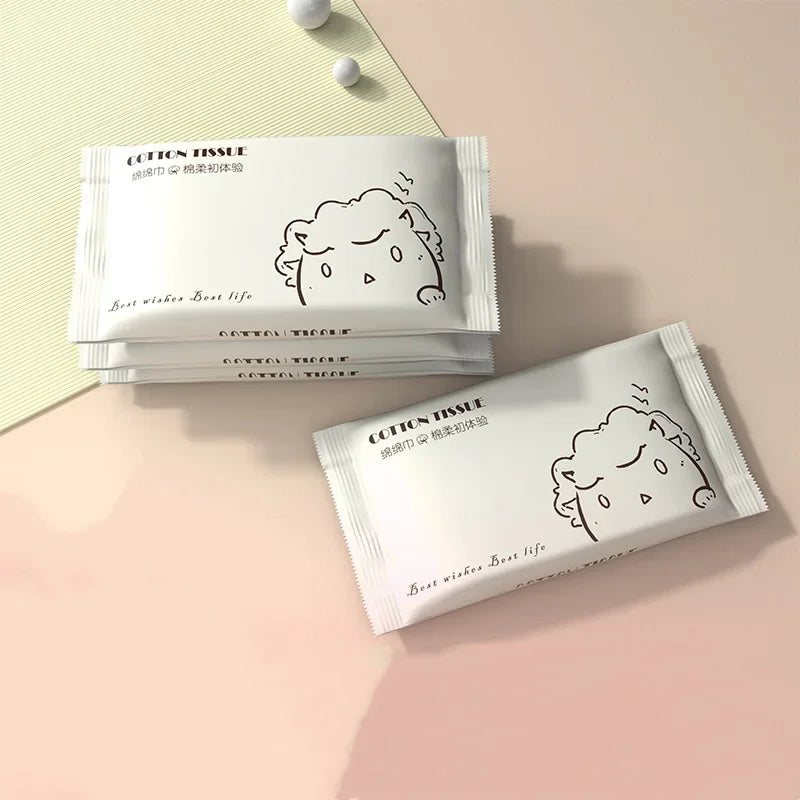 A stack of cotton tissue facial cleansing wipes is displayed on a light pink surface.