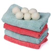 Stack of light blue and pink reusable wool dryer balls for laundry