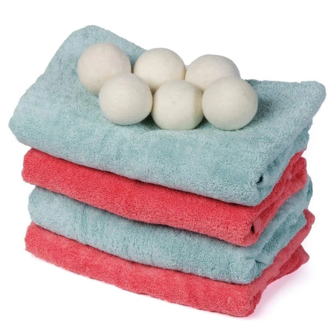 Stack of light blue and pink reusable wool dryer balls for laundry