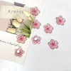 Un juego de imanes de flores de cerezo rosa para nevera con diseños florales blancos y rosas.