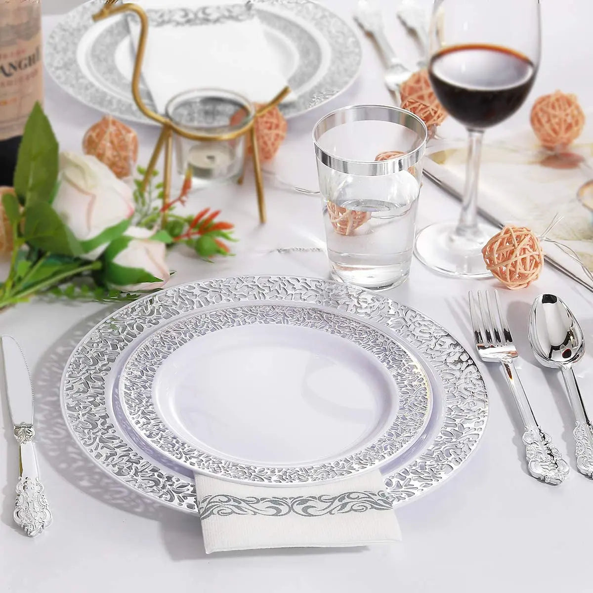 Set dekorativer Einwegpartyteller mit silberner Spitzenverzierung auf weißem Tischtuch.