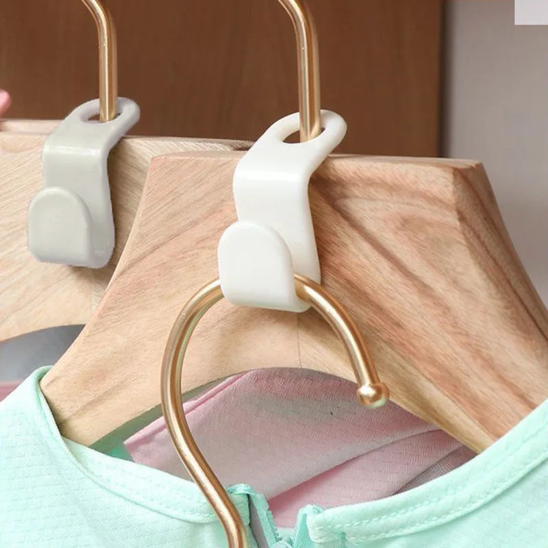 Gold-toned plastic clothes hanger hooks attached to a wooden hanger, used for wardrobe organization.