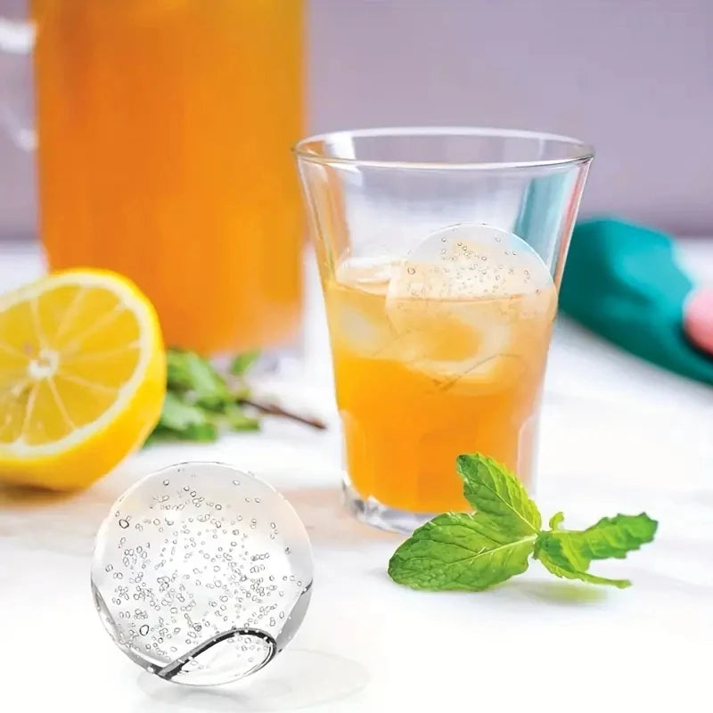A glass of orange juice with ice and a silicone mold for making ice cubes is displayed on a white surface.