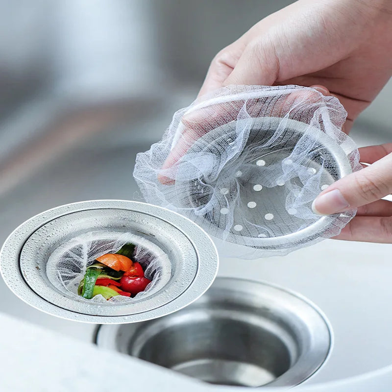 A hand is placing a mesh disposable sink drain filter bag into a metal sink drain.