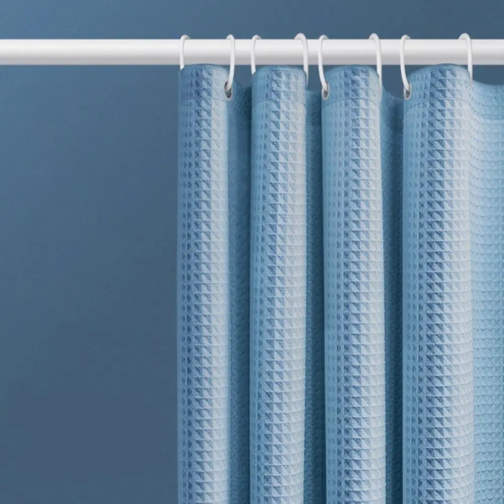 Light blue waterproof shower curtain hanging on a white rod