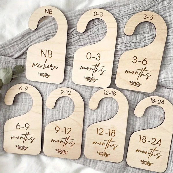 Seven wooden closet dividers for baby wardrobe labeled with age ranges from newborn to 24 months