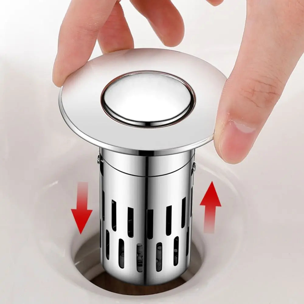 A hand is holding a round metal sink drain strainer with a removable filter, showing its top and bottom view.