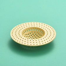 Colador de desagüe para fregadero de cocina redondo y beige claro con malla perforada para cabello.