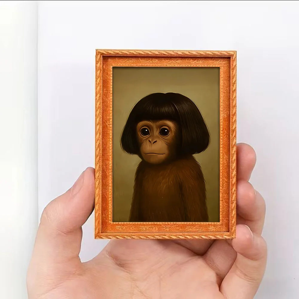A hand holds a framed illustration of a monkey in a wooden frame.