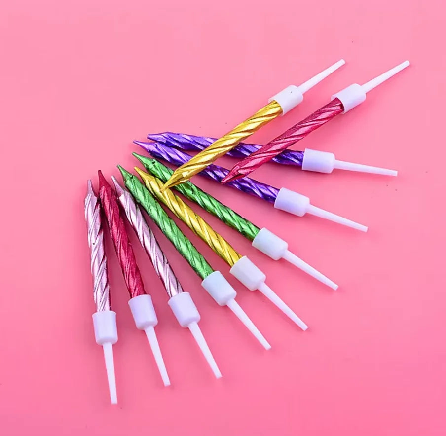 Eine Sammlung dekorativer spiralförmiger Geburtstagskerzen in verschiedenen Farben wie Gold, Lila, Rosa und Grün diagonal ang