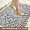 A gray waffle weave non-slip bathroom rug with a bare foot resting on it.