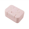 A pink ceramic soap dish with a lid featuring a smiling face.