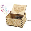 A vintage engraved wooden music box with an open lid featuring a handwritten note and a small metal mechanism.