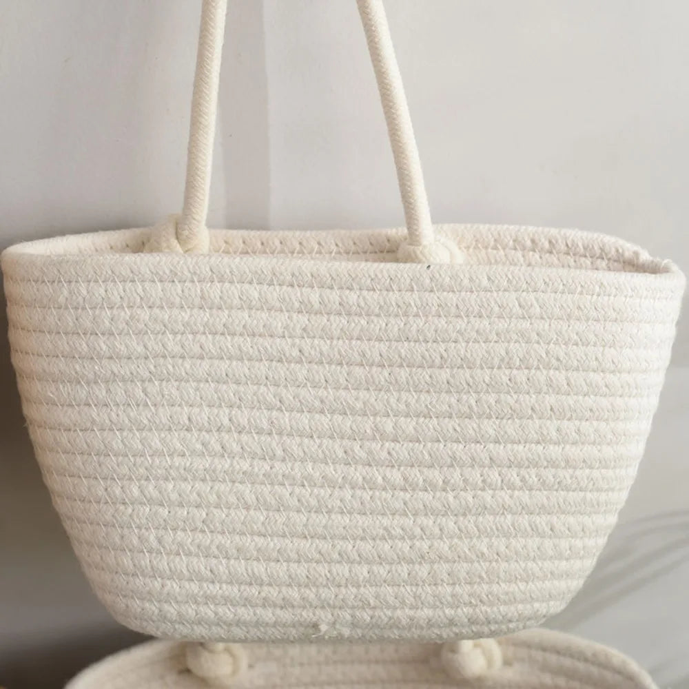 A white handwoven multi-layer wall storage basket with light beige fabric handles.
