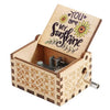 A small wooden music box with a lid featuring the text You are my sunshine and an engraved design.
