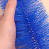 A hand holds a bright blue bendable fan brush with fine bristles.