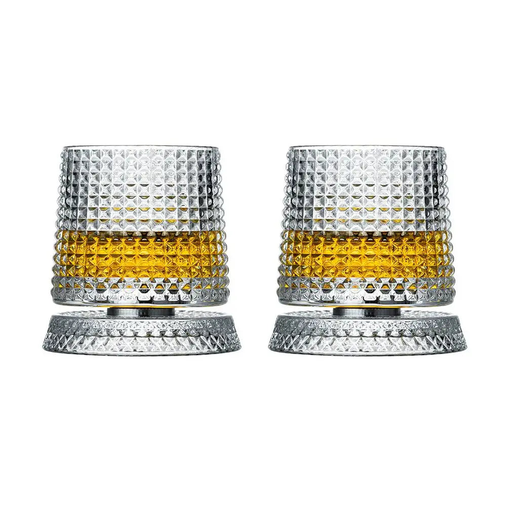 Un par de vasos de whisky texturizados y facetados con líquido de tono dorado.