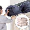 Une personne tient un sac de lessive et de rangement en nylon bleu foncé, rempli de vêtements pliés.