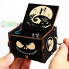 A dark wooden music box with an open lid featuring a skull design and a circular illustration of a witch flying under a moon.