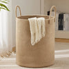 A large woven storage hamper in beige with handles and a white fringed towel resting inside.
