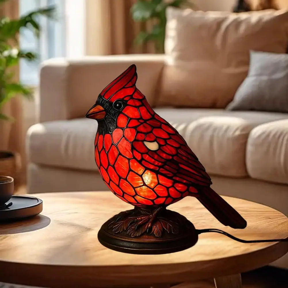 A decorative resin bird table lamp shaped like a red and black bird sitting on a wooden table.