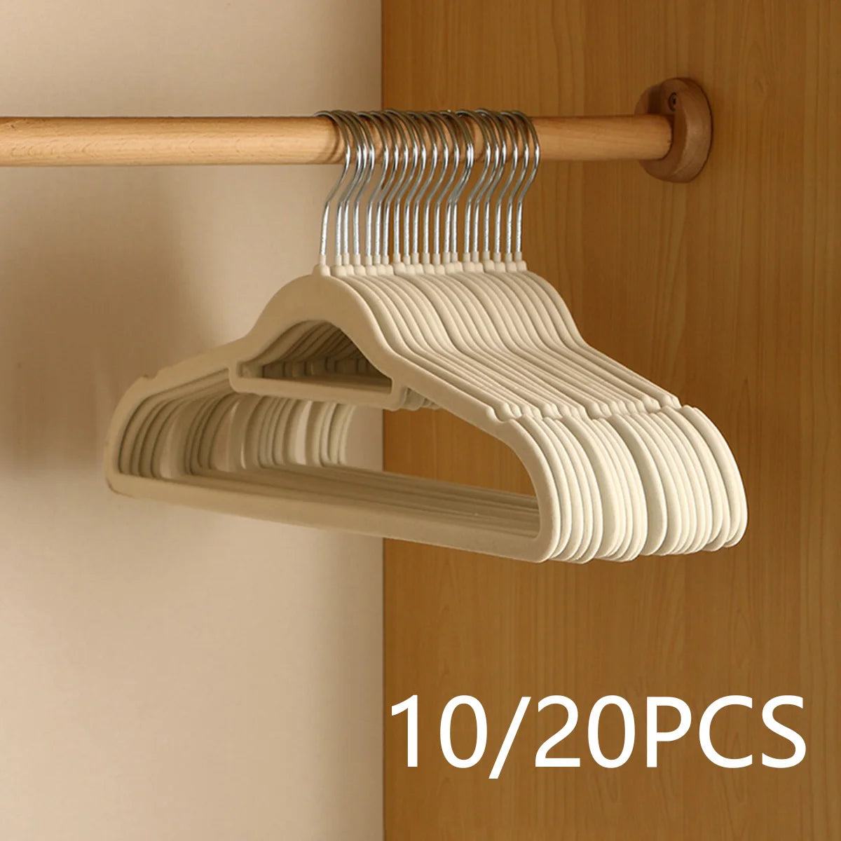 A set of ten velvet slim hangers with silver hooks hanging from a wooden rod on a cabinet door.
