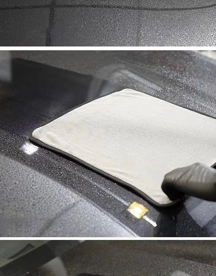 A microfiber car cleaning and drying towel is placed on a dark car surface, with a small yellow cleaning pad visible nearby.
