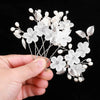A set of pearl and silver floral bridal hair clips displayed in a hand.