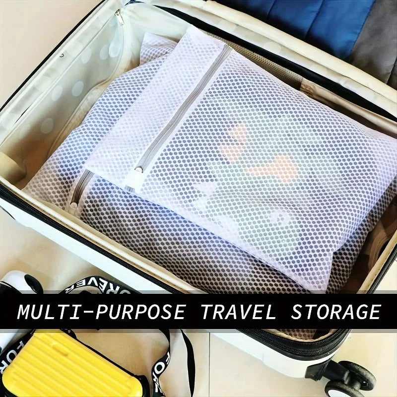 Una caja de almacenamiento de viaje abre para revelar una bolsa de ropa de malla blanca estampada y un artículo de almacenami