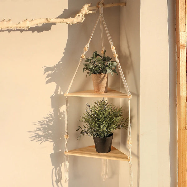 A boho triangle floating wall shelf displaying potted greenery against a light beige wall.