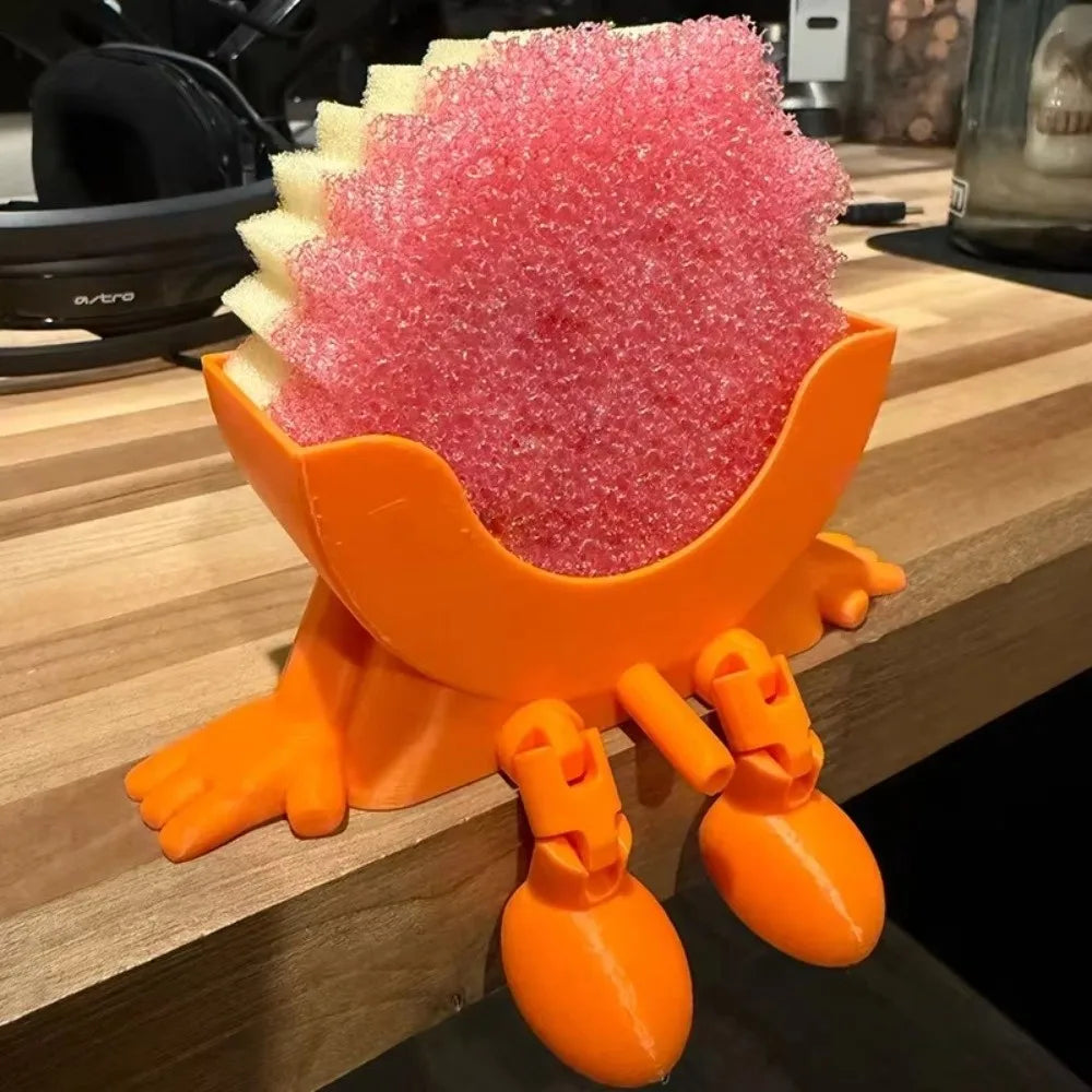An orange plastic sponge holder shaped like a fox, filled with pink exfoliating or cleaning sponges.