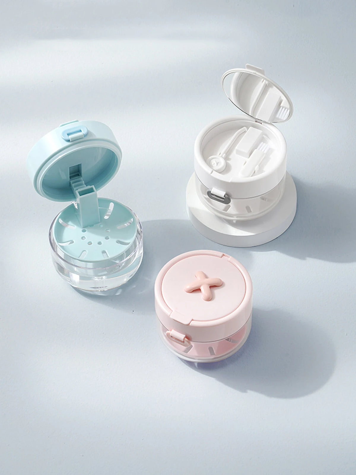 A collection of portable multi-tool organizers for dental appliances in light blue and pink colors.