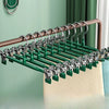 A close-up view of a green stainless steel adjustable clothing hanger rack with wooden rods and hangers.