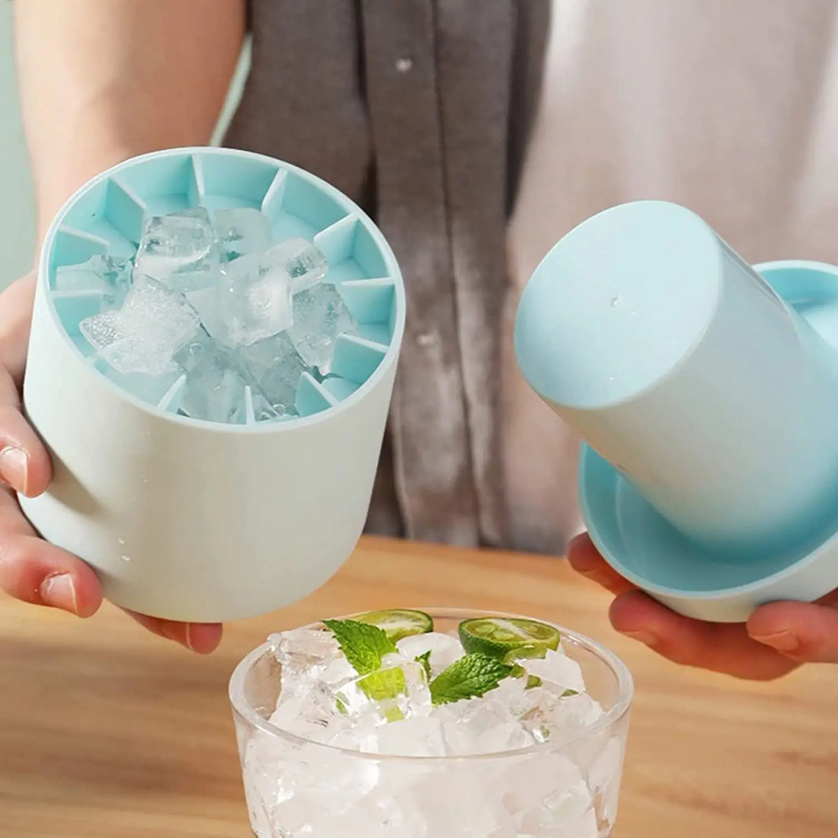 A hand holds a silicone ice cube mold set with blue ice cubes and a light blue cup.