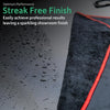 A black microfiber car drying towel with an orange trim is shown next to a wet, glossy surface.