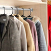 A row of various colored and textured clothing hangers hanging on a metal rack.