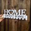 White wooden wall hook key holder with the words HOME and SWEET HOME carved into the wood
