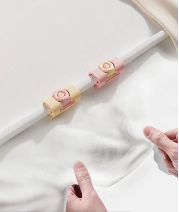 A white rod with pink and beige anti-slip clips is shown against a white fabric background.