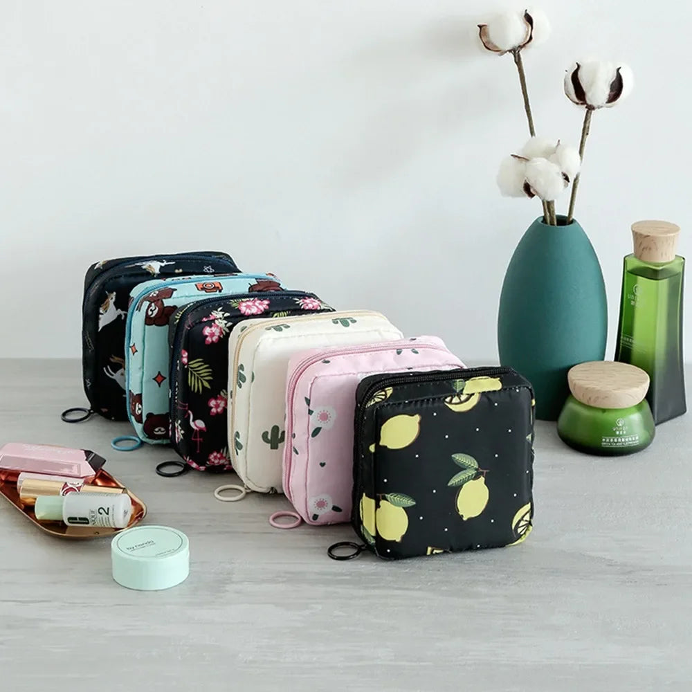 A collection of floral nylon sanitary pad storage pouches in various colors rests on a gray surface.