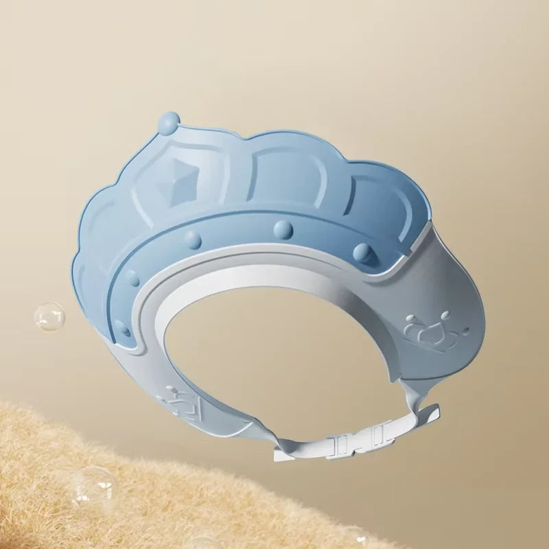 A light blue adjustable baby bath shampoo shield cap is shown against a beige background.