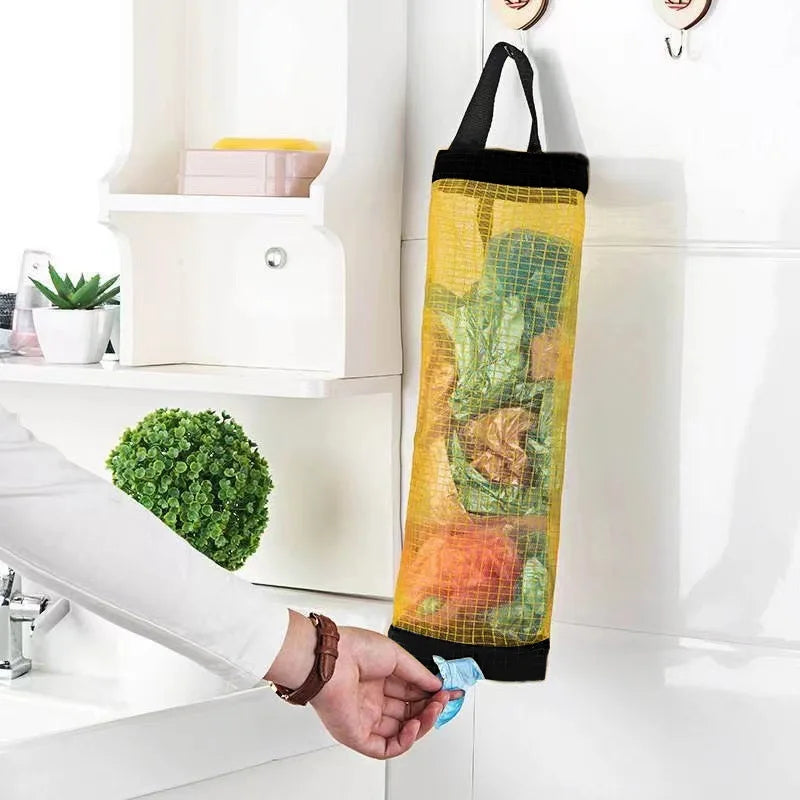 Un distributeur de sacs de courses en filet jaune avec une sangle noire est tenu par une personne dans une cuisine.