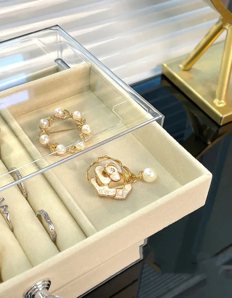 A light beige jewelry organizer box displaying gold and pearl rings and bracelets.