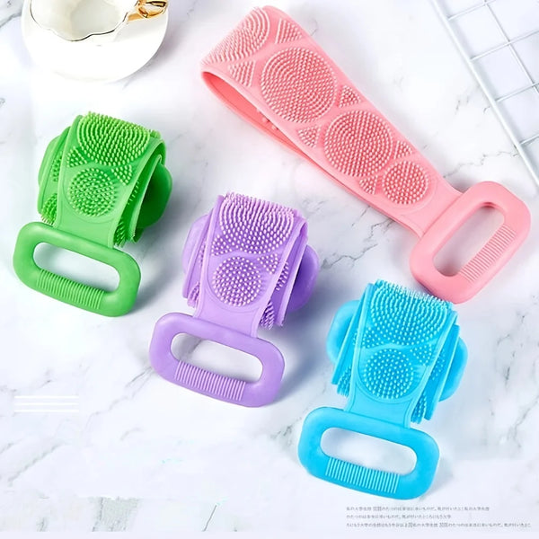 A collection of silicone body scrubbers and bath brushes in green, purple, and blue are displayed on a white marble surface.